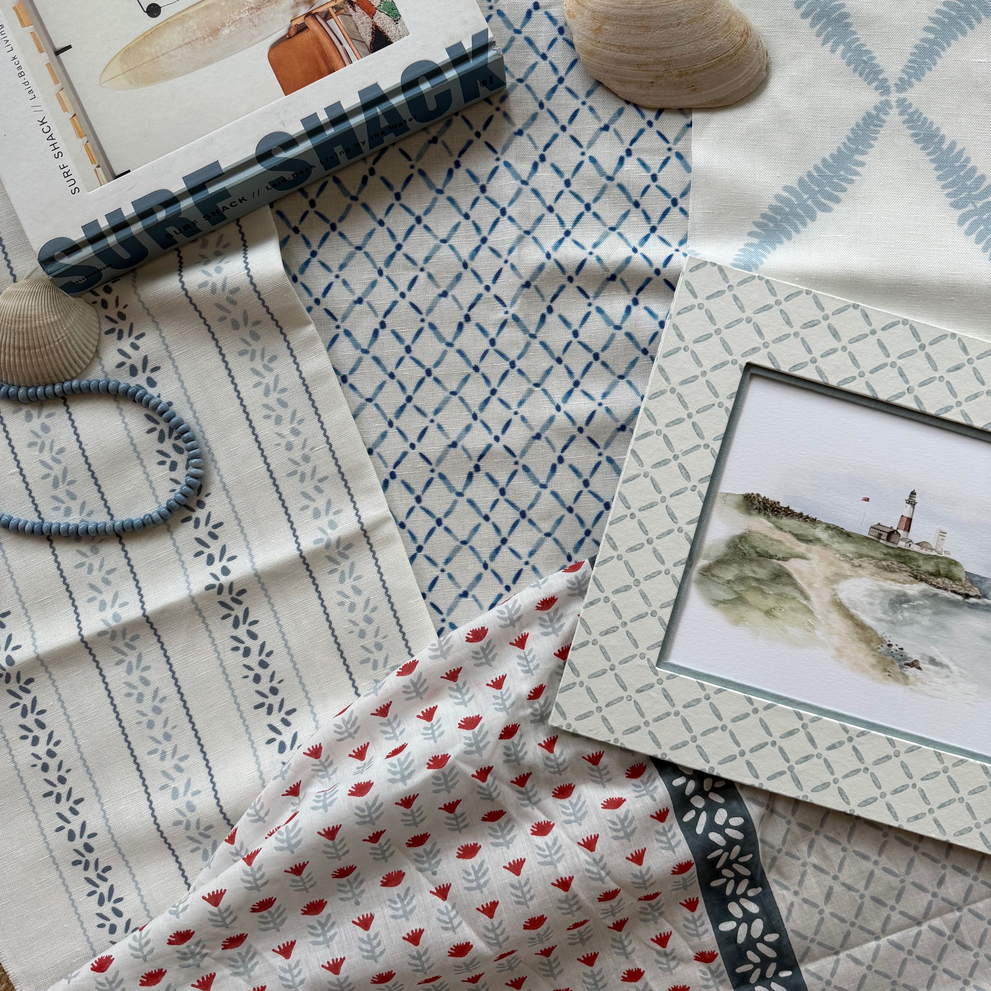 Fabric swatches with different patterns and a framed picture on a textured surface.