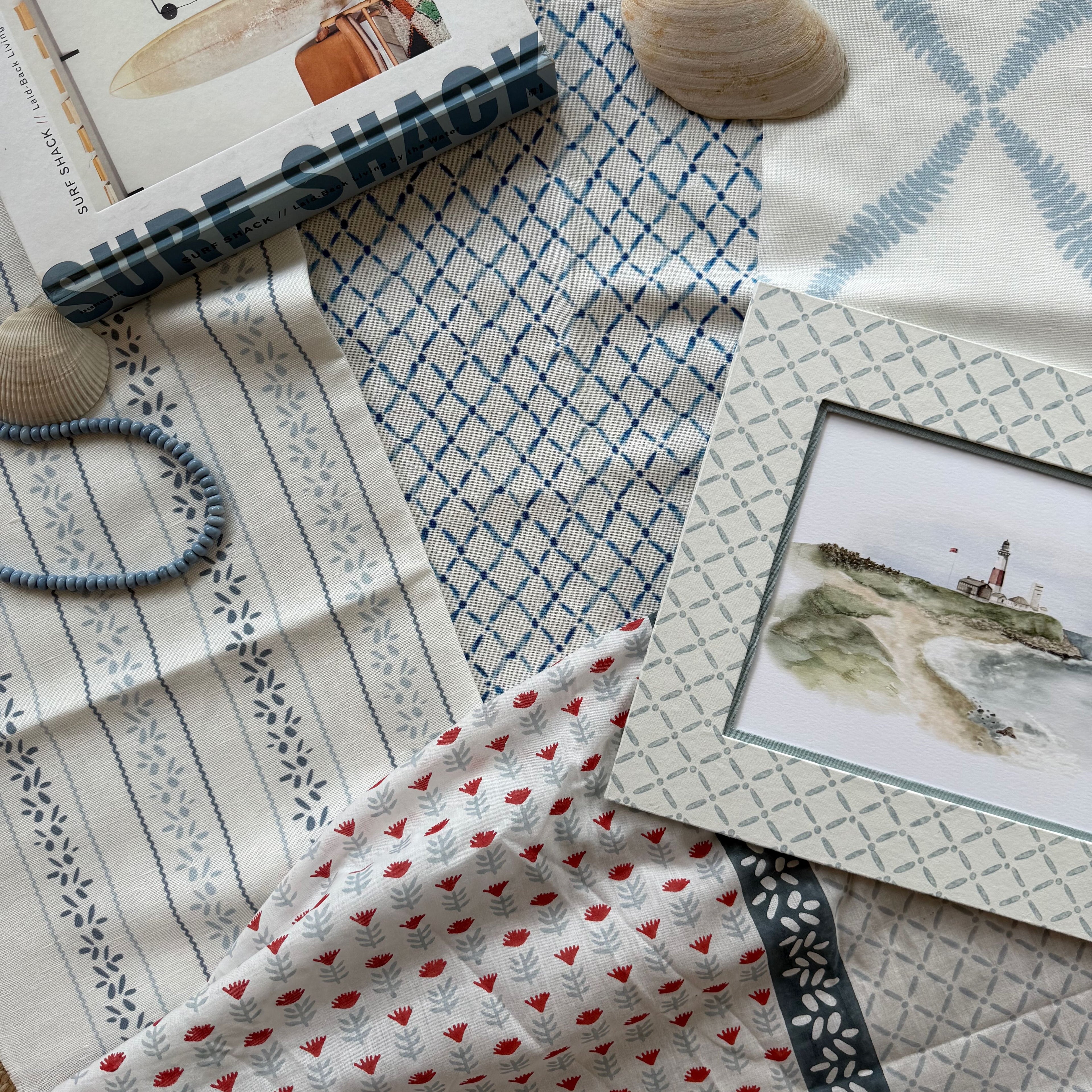 Fabric swatches with different patterns and a framed picture on a textured surface.